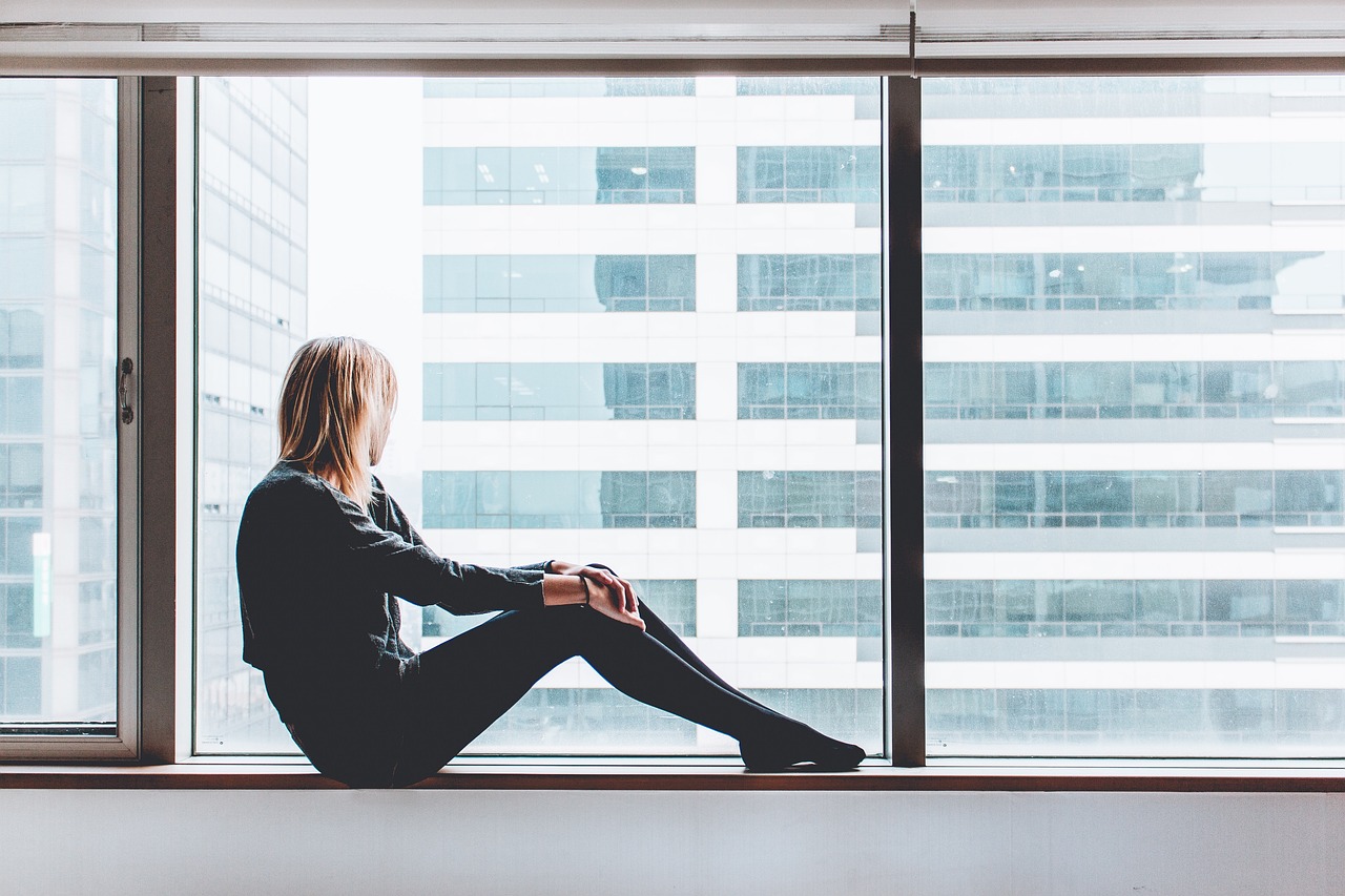 une femme regarde par la fenêtre depuis son appartement